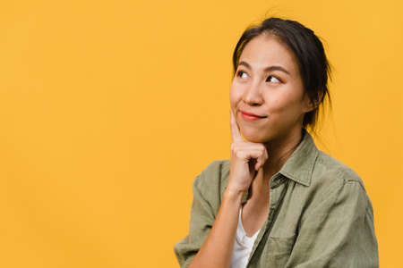 Portrait of young Asia lady with positive expression, smile broadly, dressed in casual clothing over yellow background. Happy adorable glad woman rejoices success. Facial expression concept.の写真素材