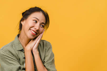 Portrait of young Asia lady with positive expression, smile broadly, dressed in casual clothing over yellow background. Happy adorable glad woman rejoices success. Facial expression concept.の写真素材