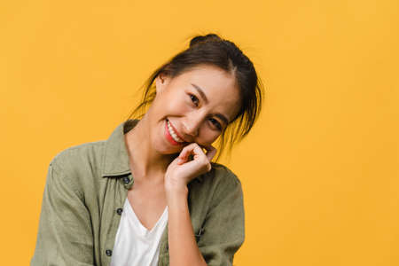 Young Asia lady with positive expression, smile broadly, dressed in casual clothing and looking at camera over yellow background. Happy adorable glad woman rejoices success. Facial expression concept.の写真素材