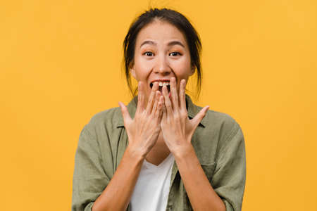 Young Asia lady feel happiness with positive expression, joyful surprise funky, dressed in casual cloth and looking at camera isolated on yellow background. Happy adorable glad woman rejoices success.の写真素材