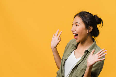 Young Asia lady feel happiness with positive expression, joyful surprise funky, dressed in casual cloth isolated on yellow background. Happy adorable glad woman rejoices success. Facial expression.の写真素材