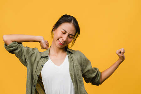 Young Asia lady with positive expression, joyful and exciting, dressed in casual cloth over yellow background with empty space. Happy adorable glad woman rejoices success. Facial expression concept.の写真素材