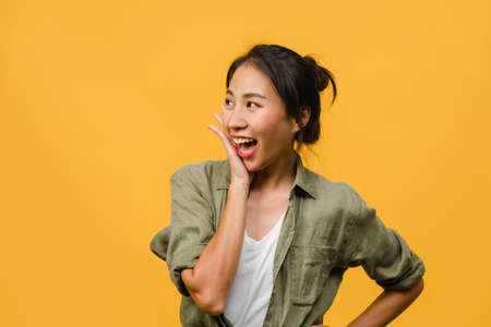 Young Asia lady feel happiness with positive expression, joyful surprise funky, dressed in casual cloth isolated on yellow background. Happy adorable glad woman rejoices success. Facial expression.の写真素材