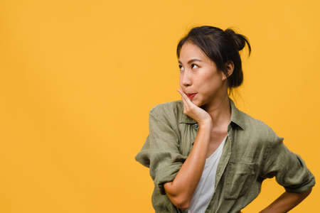 Portrait of young Asia lady with negative expression, excited screaming, crying emotional angry in casual clothing isolated on yellow background with blank copy space. Facial expression concept.の写真素材