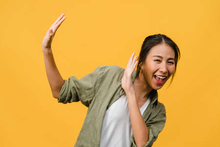 Young Asia lady feel happiness with positive expression, joyful surprise funky, dressed in casual cloth and looking at camera isolated on yellow background. Happy adorable glad woman rejoices success.の写真素材