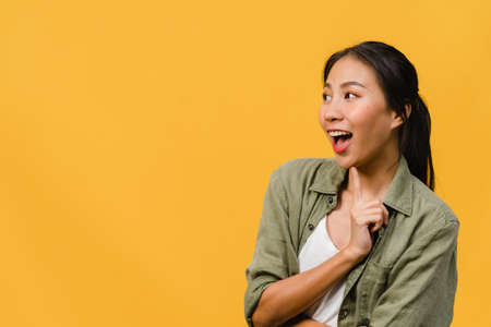 Young Asia lady feel happiness with positive expression, joyful surprise funky, dressed in casual cloth isolated on yellow background. Happy adorable glad woman rejoices success. Facial expression.の写真素材