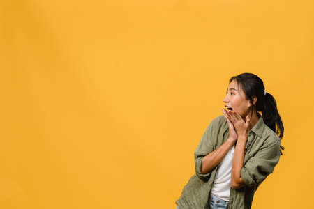 Young Asia lady feel happiness with positive expression, joyful surprise funky, dressed in casual cloth isolated on yellow background. Happy adorable glad woman rejoices success. Facial expression.の写真素材