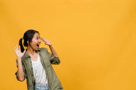 Young Asia lady feel happiness with positive expression, joyful surprise funky, dressed in casual cloth isolated on yellow background. Happy adorable glad woman rejoices success. Facial expression.の写真素材