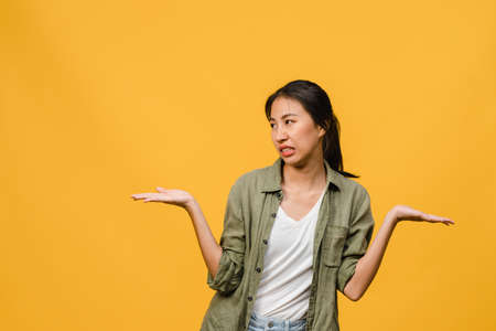 Portrait of young Asia lady with negative expression, excited screaming, crying emotional angry in casual clothing isolated on yellow background with blank copy space. Facial expression concept.の写真素材