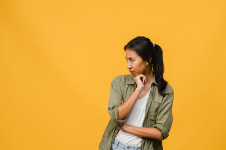 Portrait of young Asia lady with negative expression, excited screaming, crying emotional angry in casual clothing isolated on yellow background with blank copy space. Facial expression concept.の写真素材