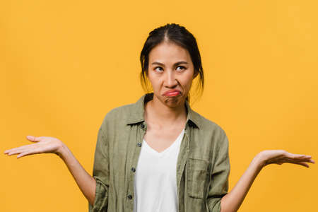 Portrait of young Asia lady with negative expression, excited screaming, crying emotional angry in casual clothing isolated on yellow background with blank copy space. Facial expression concept.の写真素材