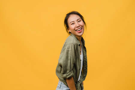 Young Asia lady with positive expression, smile broadly, dressed in casual clothing and looking at camera over yellow background. Happy adorable glad woman rejoices success. Facial expression concept.の写真素材