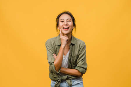 Portrait of young Asia lady with positive expression, arms crossed, smile broadly, dressed in casual clothing and looking at camera over yellow background. Happy adorable glad woman rejoices success.の写真素材