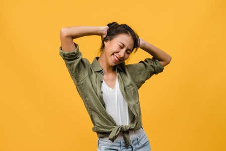 Portrait of young Asia lady with positive expression, smile broadly, dressed in casual clothing over yellow background. Happy adorable glad woman rejoices success. Facial expression concept.の写真素材