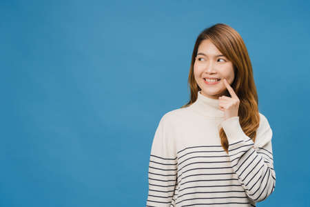 Young Asia lady showing smile, positive expression, dressed in casual clothing and fun feeling isolated on blue background. Happy adorable glad woman rejoices success. Facial expression concept.の写真素材