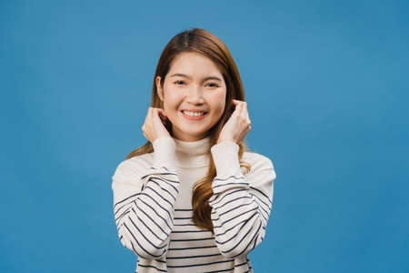 Young Asia lady with positive expression, smile broadly, dressed in casual clothing and looking at camera over blue background. Happy adorable glad woman rejoices success. Facial expression concept.の写真素材