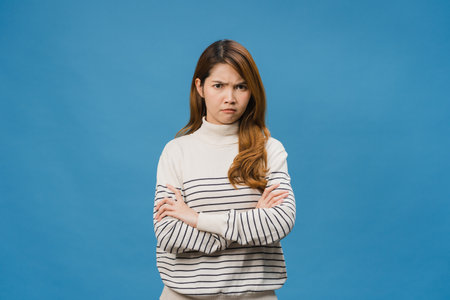 Young Asia lady with negative expression, excited screaming, crying emotional angry in casual clothing and looking at camera isolated on blue background. Happy adorable glad woman rejoices success.の写真素材