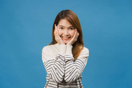Young Asia lady with positive expression, smile broadly, dressed in casual cloth and look at camera isolated on blue background. Happy adorable glad woman rejoices success. Facial expression concept.の写真素材