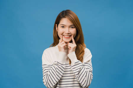 Young Asia lady showing smile, positive expression, dressed in casual cloth and look at camera isolated on blue background. Happy adorable glad woman rejoices success. Facial expression concept.の写真素材