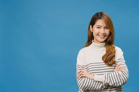 Portrait of young Asia lady with positive expression, arms crossed, smile broadly, dressed in casual clothing and looking at camera over blue background. Happy adorable glad woman rejoices success.の写真素材