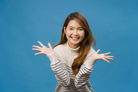 Young Asia lady feeling happiness with positive expression, joyful and exciting, dressed in casual cloth and looking at camera isolated on blue background. Happy adorable glad woman rejoices success.の写真素材