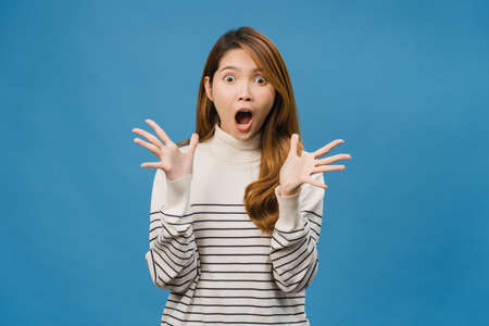 Young Asia lady feeling happiness with positive expression, joyful surprise funky, dressed in casual cloth and looking at camera isolated on blue background. Happy adorable glad woman rejoices successの写真素材
