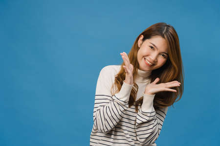 Young Asia lady with positive expression, smile broadly, dressed in casual cloth and look at camera isolated on blue background. Happy adorable glad woman rejoices success. Facial expression concept.の写真素材