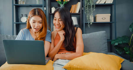 Teenager Asian women feeling happy smiling selfie and looking to camera while relax in living room at home. Cheerful Roommate ladies video call with friend and family, Lifestyle woman at home concept.の写真素材