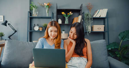 Teenager Asian women feeling happy smiling selfie and looking to camera while relax in living room at home. Cheerful Roommate ladies video call with friend and family, Lifestyle woman at home concept.の写真素材