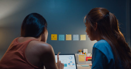 Happy attractive Asia women with casual relax on couch chat talk together about their life and relationship gossip in living room at house night. Girls friends roommate stay in dorm together.の写真素材