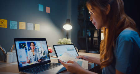 Happy attractive Asia women with casual relax on couch chat talk together about their life and relationship gossip in living room at house night. Girls friends roommate stay in dorm together.の写真素材