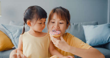 Happy cheerful Asia family mom teach toddler girl paint ceramic pot having fun relax on table in living room at house. Spending time together, Social distance, Quarantine for coronavirus prevention.の写真素材