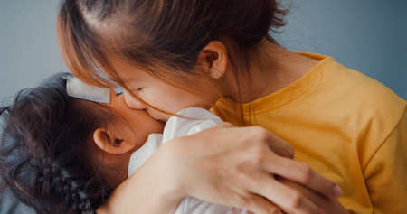 Happy cheerful Asia family mom teach girl paint use album and colourful pencils having fun relax on couch in living room at house. Spending time together, Social distance, Quarantine for coronavirus.の写真素材