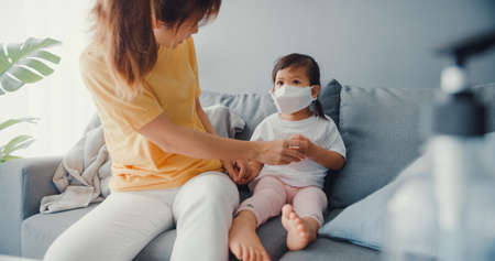 Happy cheerful Asia family mom teach girl paint use album and colourful pencils having fun relax on couch in living room at house. Spending time together, Social distanceの写真素材