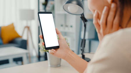 Asia businesswoman using laptop with blank white screen mock up display for advertising text talk to colleagues about plan in video call meeting at living room at house. Working overload at night.の写真素材