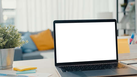 Asia businesswoman using laptop with blank white screen mock up display for advertising text talk to colleagues about plan in video call meeting at living room at house. Working overload at night.の写真素材