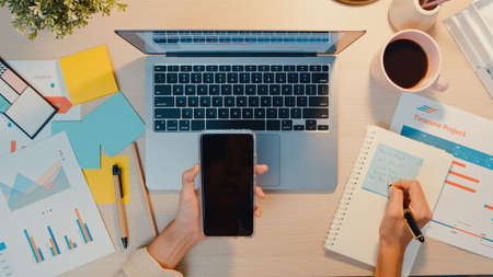 Asia businesswoman using laptop with blank white screen mock up display for advertising text talk to colleagues about plan in video call meeting at living room at house. Working overload at night.の写真素材
