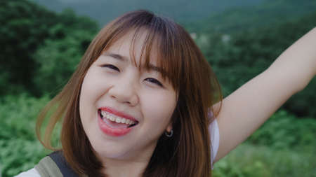 Attractive casual happy young Asian woman in international airport, using and checking her smartphone standing in terminal hall while waiting for her flight to board airplane at the departure gate.の写真素材