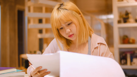 Attractive casual happy young Asian woman in international airport, using and checking her smartphone standing in terminal hall while waiting for her flight to board airplane at the departure gate.の写真素材