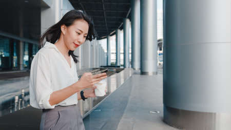 Young Asian woman drinking orange juice in the kitchen, beautiful female in sport clothing use organic fruits lots of nutrition making orange juice by herself at home. Healthy food concept.の写真素材