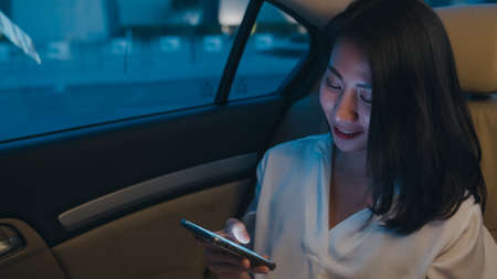 Young Asian woman drinking orange juice in the kitchen, beautiful female in sport clothing use organic fruits lots of nutrition making orange juice by herself at home. Healthy food concept.の写真素材