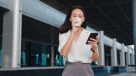 Young Asian woman drinking orange juice in the kitchen, beautiful female in sport clothing use organic fruits lots of nutrition making orange juice by herself at home. Healthy food concept.の写真素材