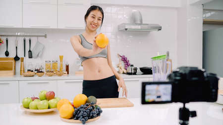 Happy Asian woman using tablet for looking recipe while making food in the kitchen, female use organic vegetable for healthy food at home. Lifestyle women making food concept.の写真素材