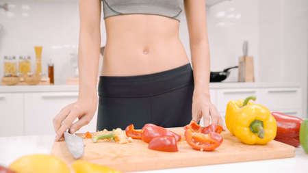 Happy Asian woman using tablet for looking recipe while making food in the kitchen, female use organic vegetable for healthy food at home. Lifestyle women making food concept.の写真素材