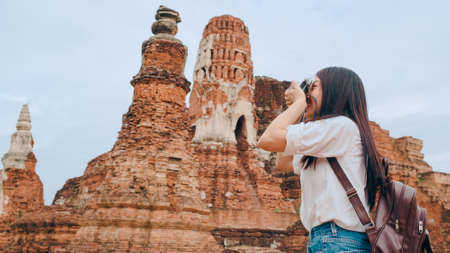 Traveler Asian woman using camera for take a picture while spending holiday trip at Ayutthaya, Thailand, Japanese female tourist enjoy her journey at amazing landmark in traditional city.の写真素材