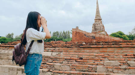 Traveler Asian woman using camera for take a picture while spending holiday trip at Ayutthaya, Thailand, Japanese female tourist enjoy her journey at amazing landmark in traditional city.の写真素材