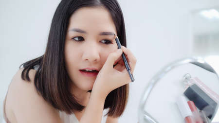 Beauty blogger present beauty cosmetics sitting in front camera for recording video. Happy beautiful young Asian woman use cosmetics review make up tutorial broadcast live video to social network.の写真素材