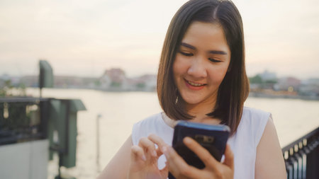 Happy young Asian woman blogger tourist with casual style hold smartphone look with smile joyful...