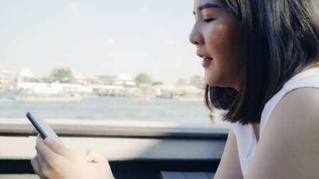 Tourist Asian women using mobile phone at outdoor cafe. Young Japanese Asia Girl using smartphone checking social media and texting with friends in social network enjoying the journey holiday travel.の写真素材