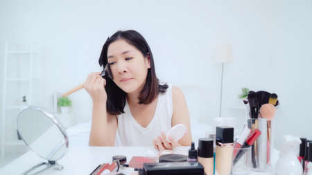 Beauty blogger present beauty cosmetics sitting in front camera for recording video. Happy beautiful young Asian woman use cosmetics review make up tutorial broadcast live video to social network.の写真素材